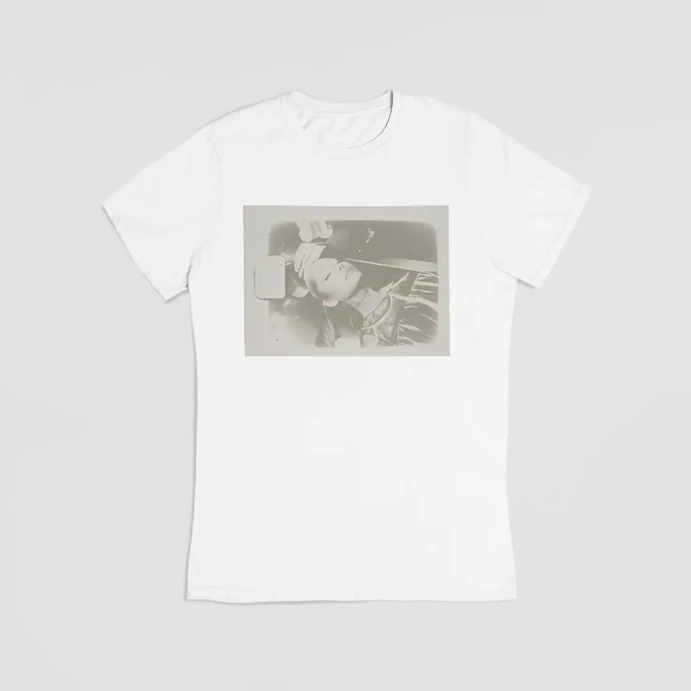 White t-shirt with black and white printed photo of a woman lying down and holding a phone.