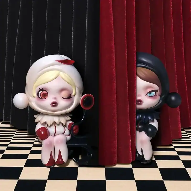 Cute collectible dolls featuring characters with distinctive outfits, placed on a checkered floor with red and black curtains in the background.