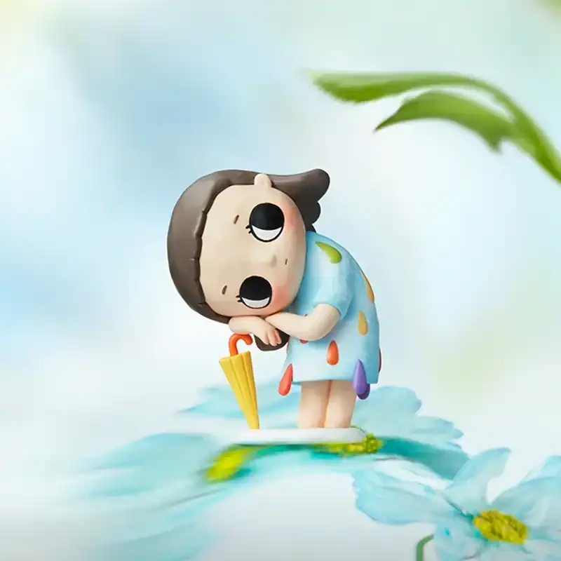 Cute cartoon girl figurine with umbrella standing in water, raincoat, and big eyes.