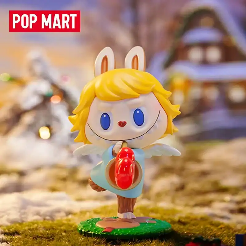 Cute bunny figurine with blonde hair, blue eyes, and a red nose, wearing a light blue dress with angel wings, holding a red object, set against a blurred festive background.