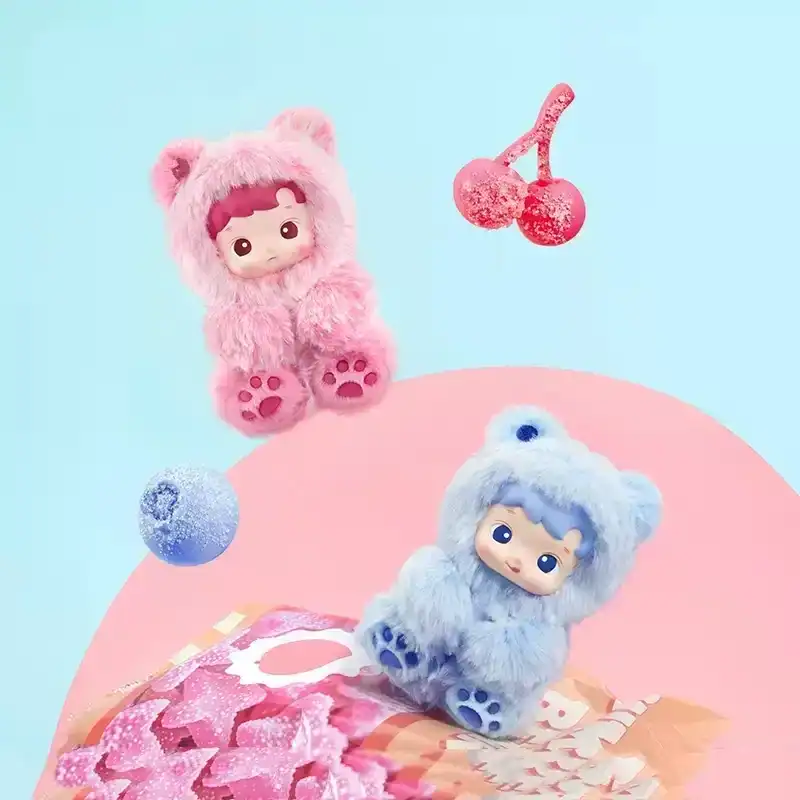 Pink plush toy with a cute face and bear ears, designed as collectible merchandise; blue plush character with similar style, both in adorable bear costumes; colorful cherry and berry props in background.